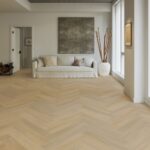 Woonkamer met spc visgraatvloer en witte bank.