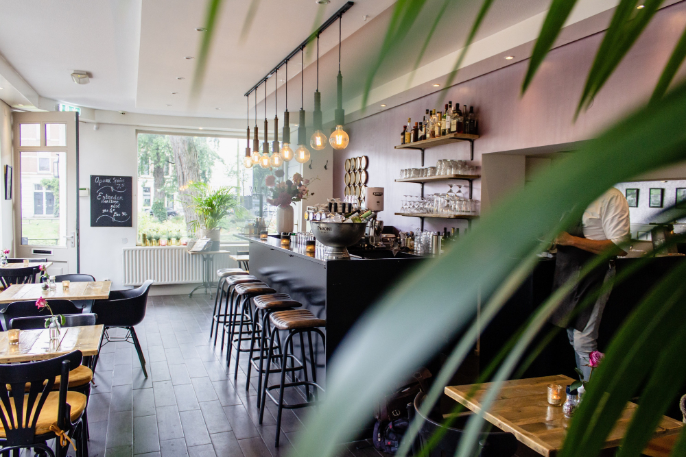 Café met donkere horecavloer en bar rechts.
